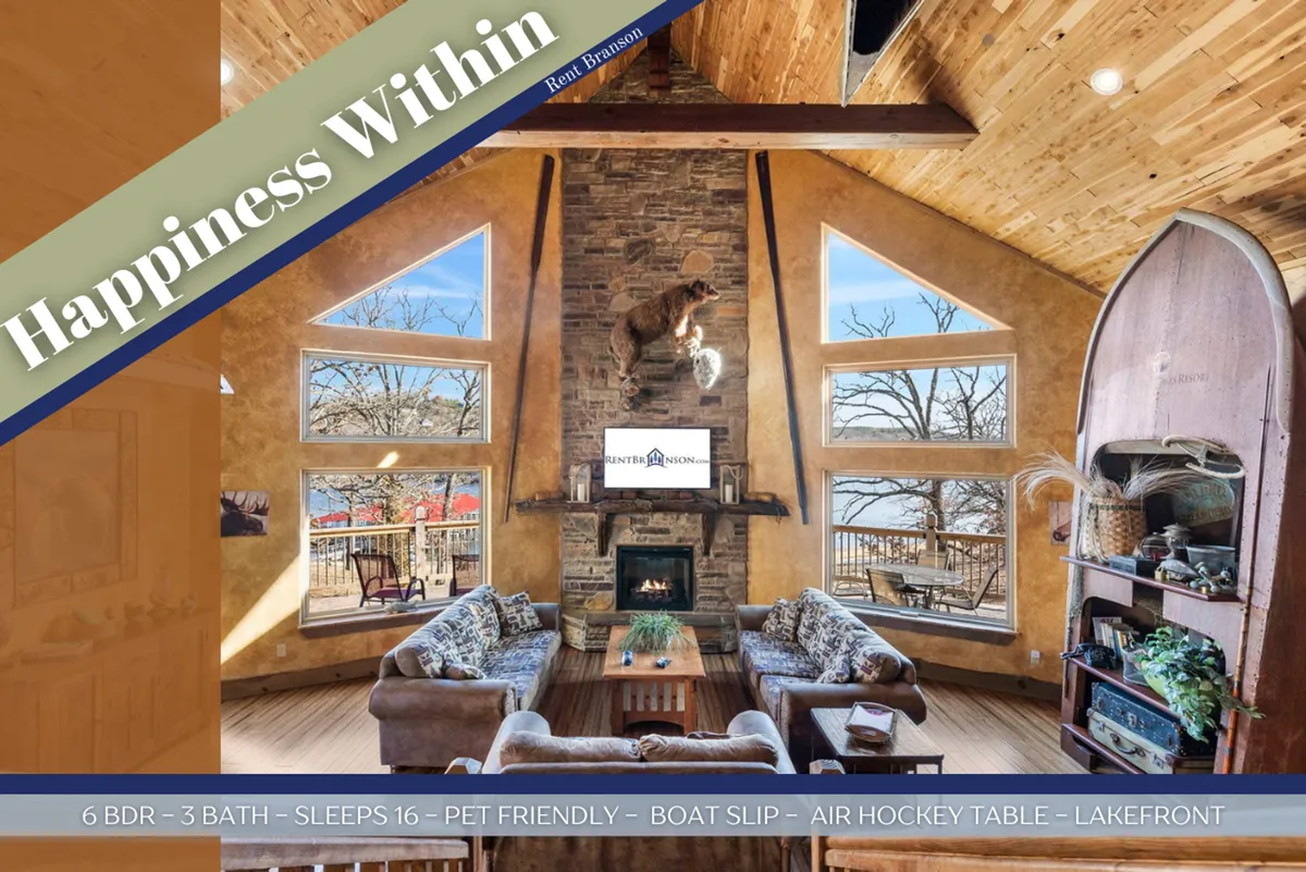 A comfortable living area with a stone fireplace, plush seating, and large windows that frame the serene lake outside. An air hockey table adds a playful touch, inviting guests to relax, socialize, and enjoy group activities.