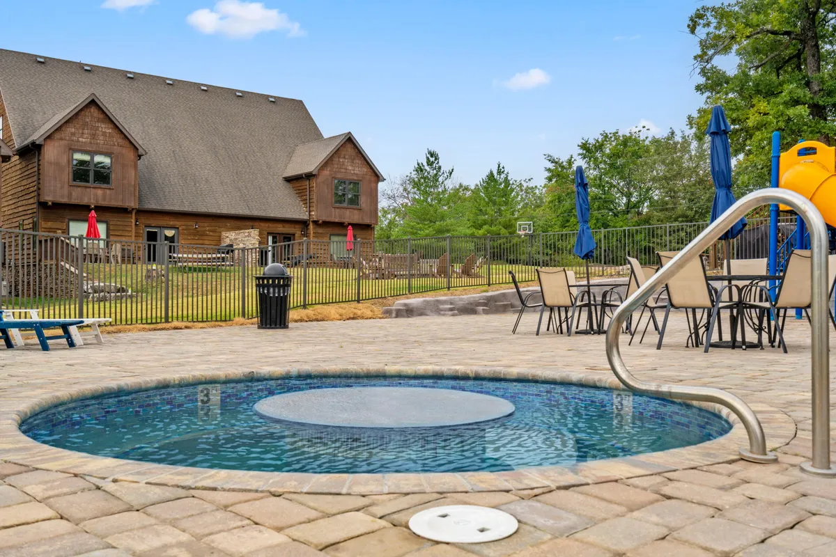 This exterior image features a sparkling swimming pool with a hot tub nearby, accompanied by lounge chairs and a children's slide. The space is brightly lit, evoking a lively summer atmosphere ideal for outdoor fun and relaxation.