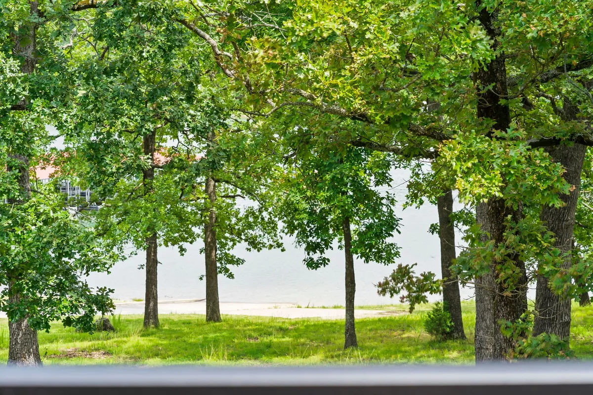 This image captures a lush, grassy area leading directly to the lake, framed by mature trees and tranquil water. The scene invites viewers to imagine taking peaceful lakeside walks or enjoying a game of fetch with their dog, all in a setting that feels safe and inviting for pets.